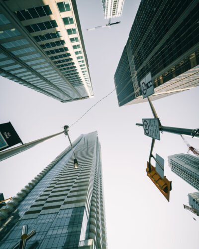 A vertical low angle shot of modern high-rise buildings in an urban neighborhood with traffic road sign